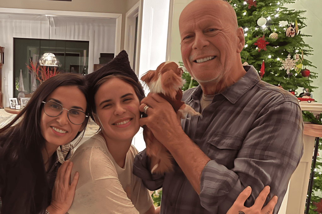 Bruce Willis, entouré de sa famille aimante, partage un moment de joie avec leur chien, près d'un arbre de Noël, illustrant le soutien familial face à sa maladie.