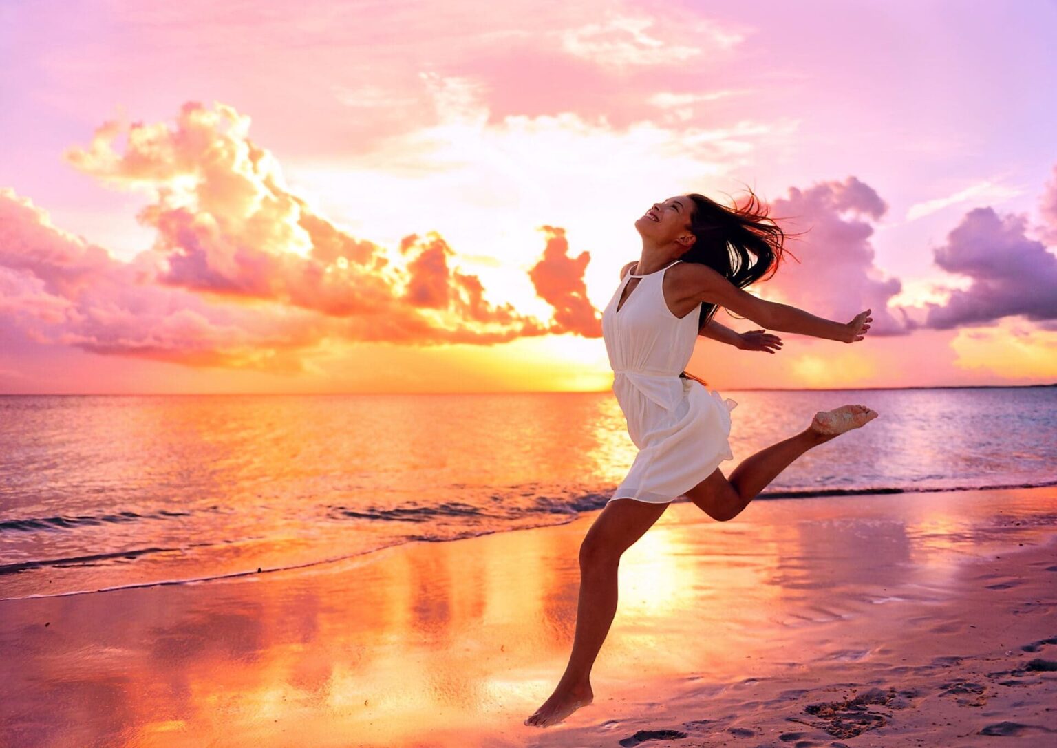 Happy beautiful woman running at beach sunset