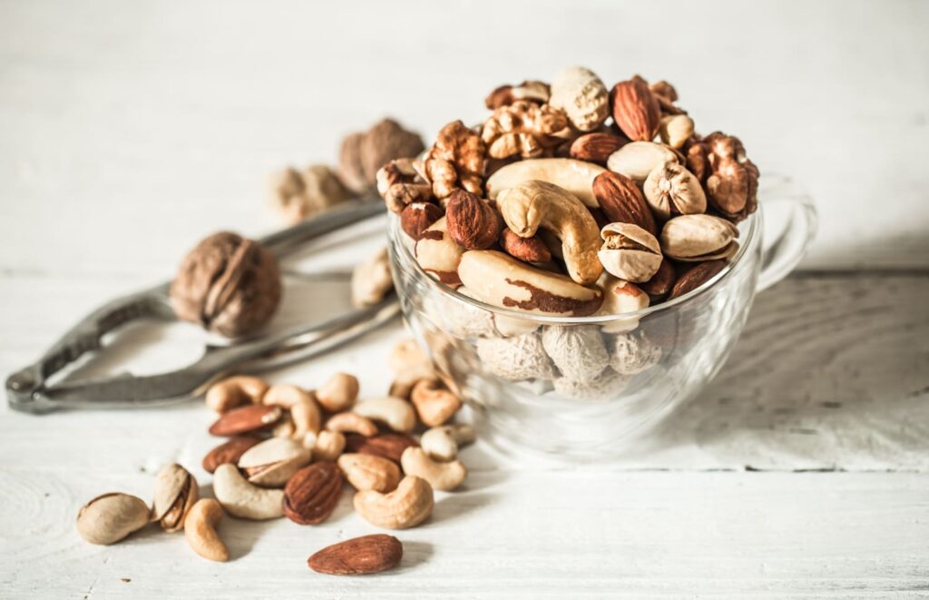 Different,Nuts,In,A,Beautiful,Transparent,Cup,On,Wood,Background