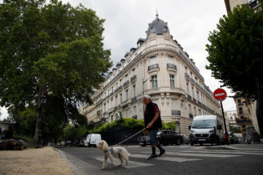 Dans cette photo d’archive du 13 août 2019, un homme promène son chien à côté d’un immeuble appartenant à Jeffrey Epstein à Paris.